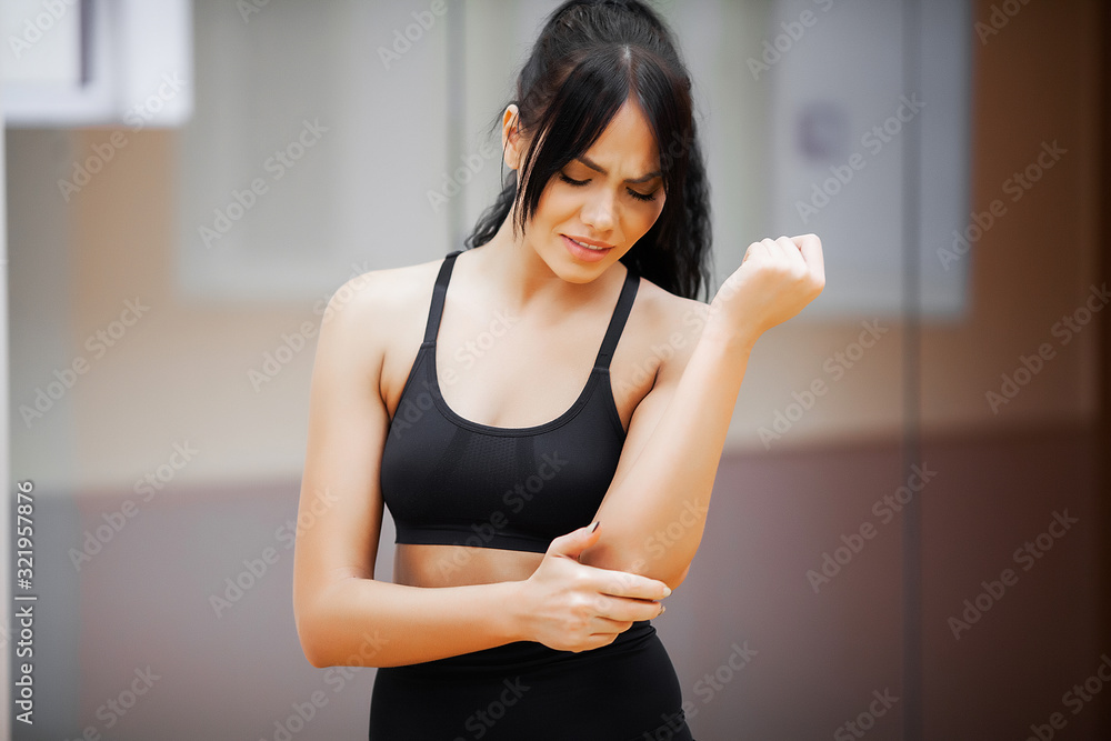 Fitness woman doing exercises in gym and feeling pain in hand. Fitness woman doing exercises in gym and feeling pain in hand.