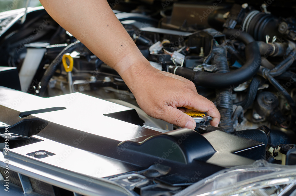 A man examining the water in a car radiator A man examining the water in a car radiator