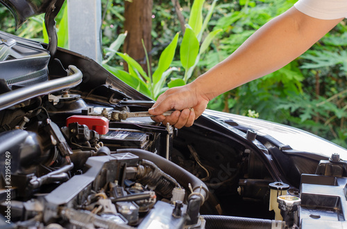 A man used a wrench to change the car battery. © Santipong