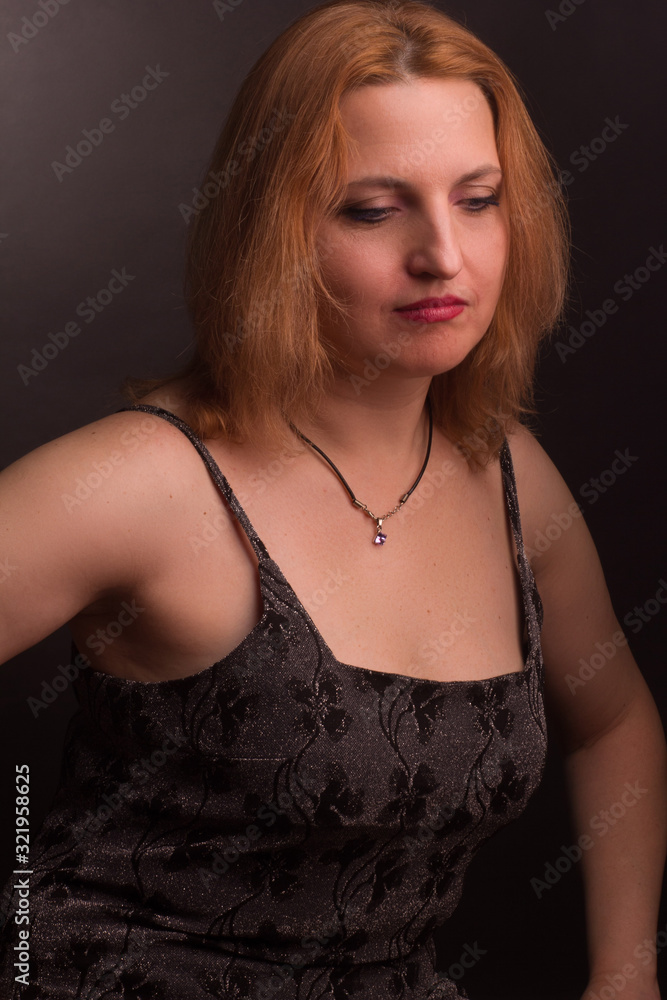 Naklejka premium portrait of large blonde model in a black dress on a dark background in the Studio