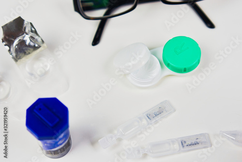 Contact lens case in a flat lay pattern with other eye care products including glasses, drops, and other cases