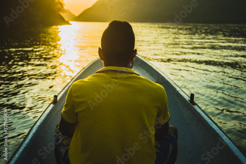 young man sitting on his back in a canoe or boat. young man sailing on the lake at sunset sunrise