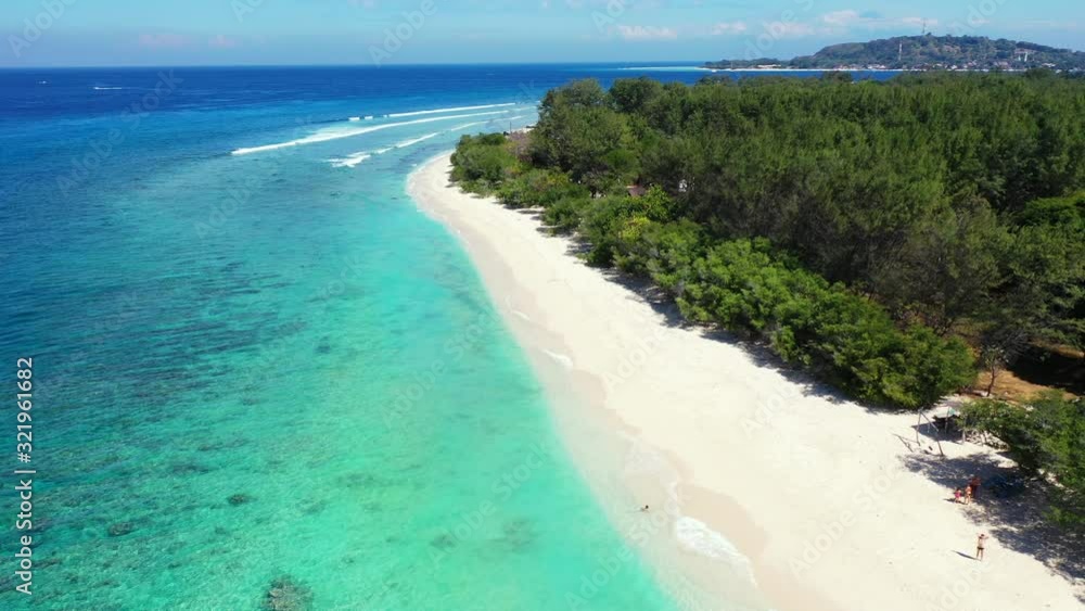 Beautiful remote exotic beach with clear blue water and white sand captured from the air with mountains in the background Beautiful remote exotic beach with clear blue water and white sand captured from the air with mountains in the background