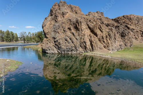 rock reflected in a small lake in central Mongolia. reflection of the stone. The beautiful landscape of Mongolia. Sunny day in autumn, blue clear sky. Mirroring of the sky in the crystal clear water