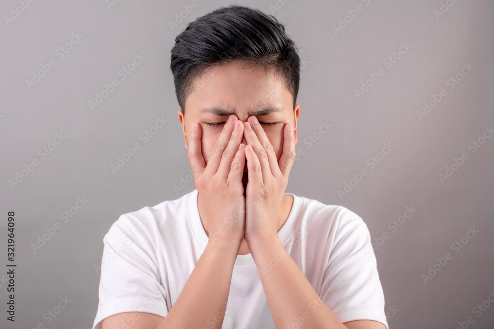 Asian people with headaches and eyes Use your hand to hide it on the gray background. Asian people with headaches and eyes Use your hand to hide it on the gray background.