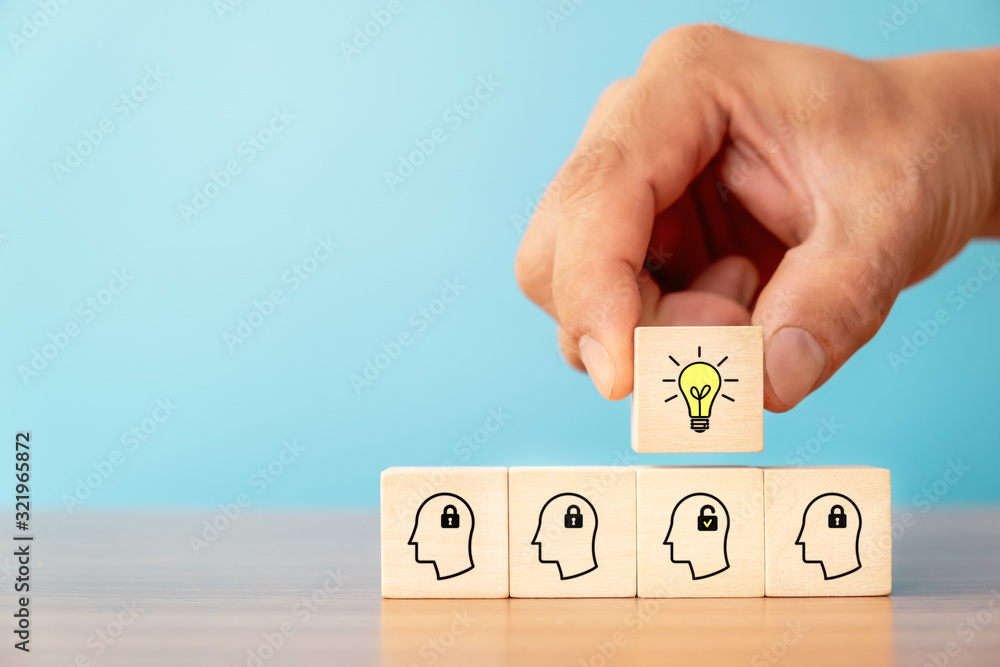 Business concept of creative idea and innovation. Hand picked wooden cube block with light bulb icon (new idea) over wood block with unlock icon and head human symbol have no idea. Business concept of creative idea and innovation. Hand picked wooden cube block with light bulb icon (new idea) over wood block with unlock icon and head human symbol have no idea.