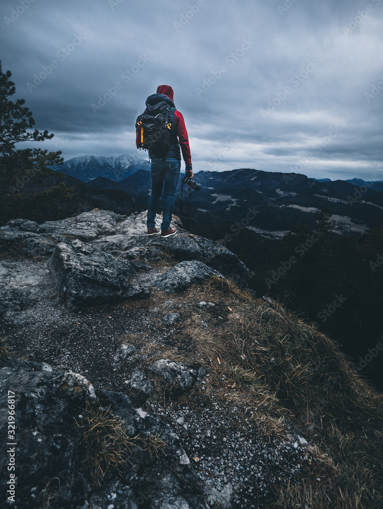man with camera stands on mountain top on a cloudy moody day man with camera stands on mountain top on a cloudy moody day