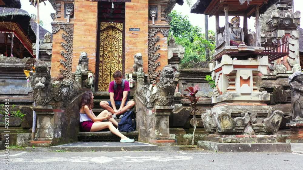 A man and woman sitting on the steps of a beautiful ancient building carved from stone