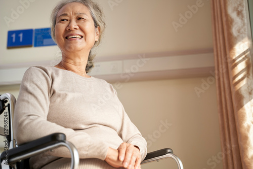 happy old woman sitting in wheelchair in nursing home photo