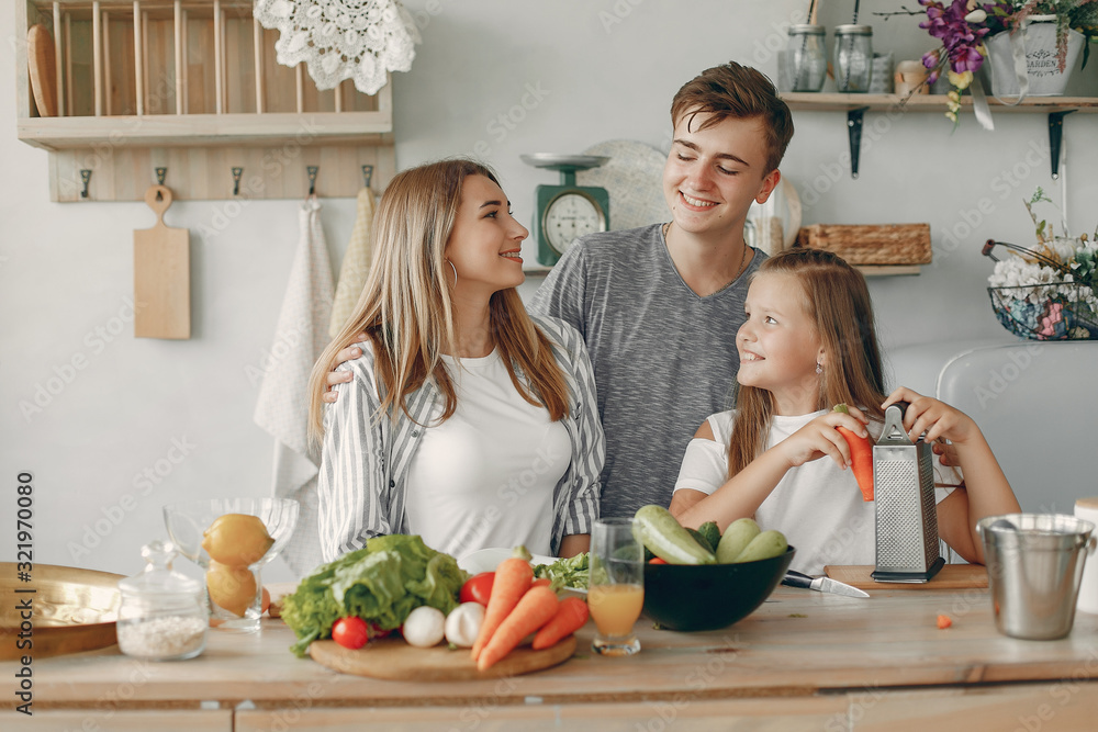 Family in a kitchen. Blonde in a white t-shirt. Woman with vegetables Family in a kitchen. Blonde in a white t-shirt. Woman with vegetables