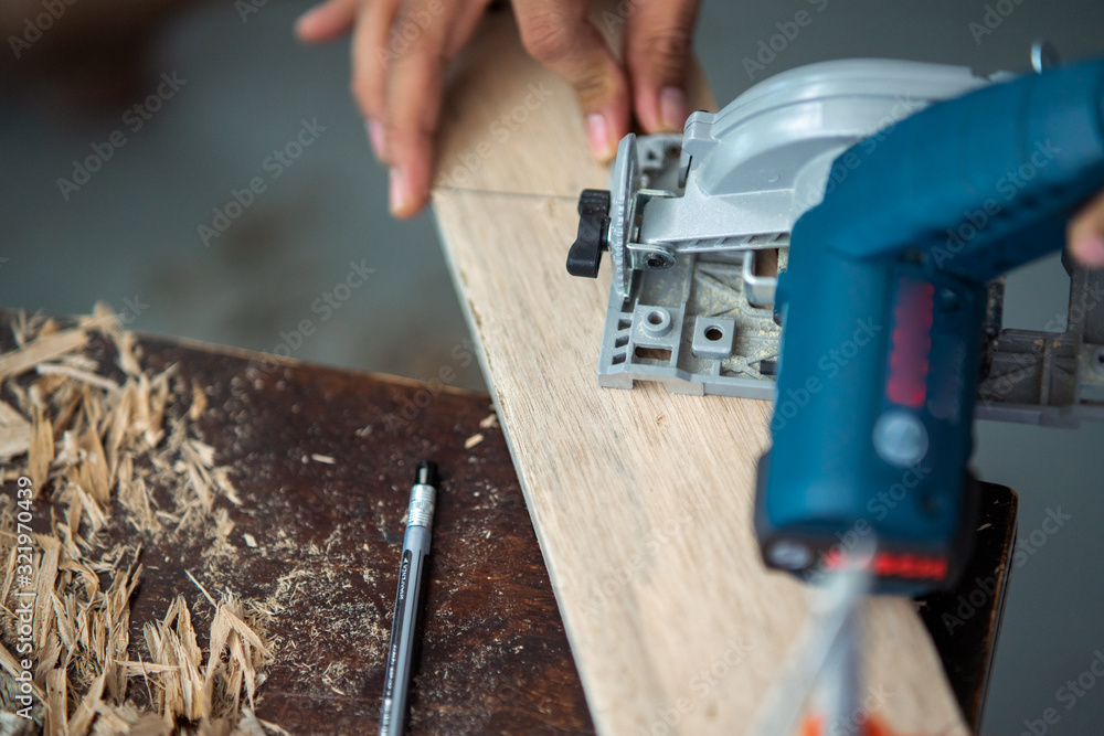 Close-up of a carpenter using a circular saw to cut a plank of wood