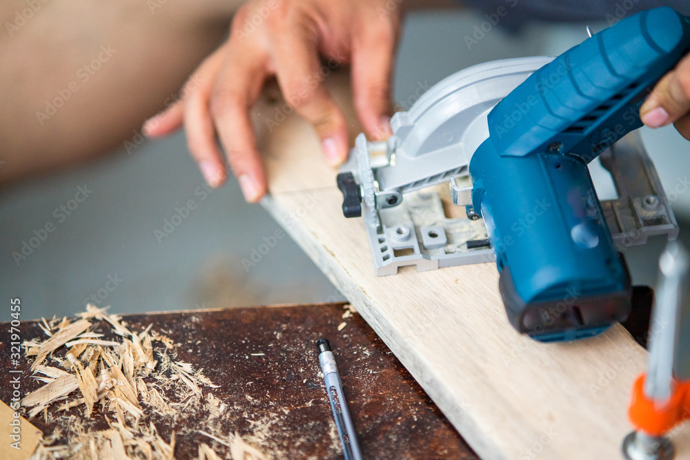Close-up of a carpenter using a circular saw to cut a plank of wood Close-up of a carpenter using a circular saw to cut a plank of wood