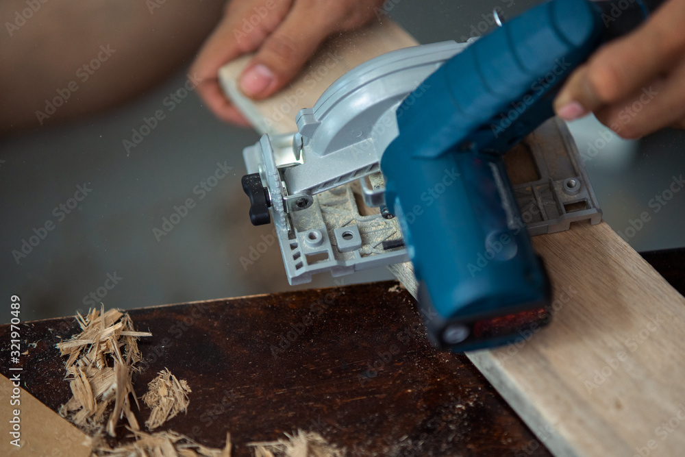 Close-up of a carpenter using a circular saw to cut a plank of wood Close-up of a carpenter using a circular saw to cut a plank of wood