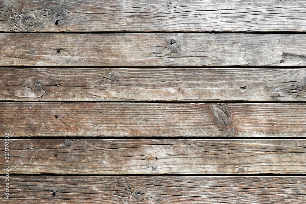 Close-up of wooden wall of rural house. Old, dry, weathered boards with deep cracks, with rusty nails driven in. Texture of wood. Abstract background. For design. empty template