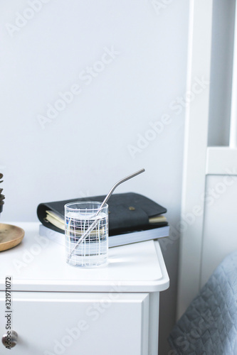 Eco natural metallic straw in glass with water on bedside table. sustainable lifestyle, zero waste, plastic free concept