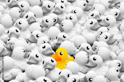 Fotografie Unique yellow toy duck among many monochrome ones