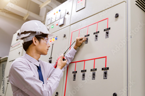 Control Room Engineer. Power Plant Control Panel. Engineer standing in front of the control panel in the control room and write the results of the measurements and check system ready . photo