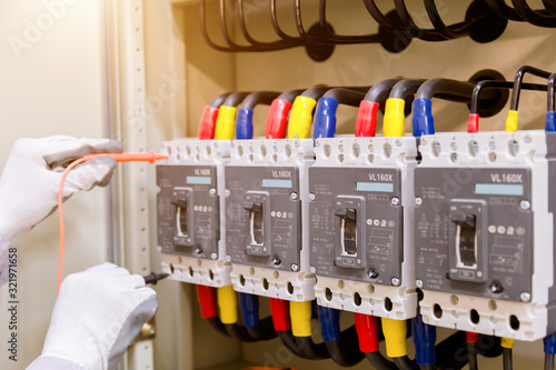 Technician is measuring voltage or current by voltmeter in control panel of power plan with checklist System ready. photo