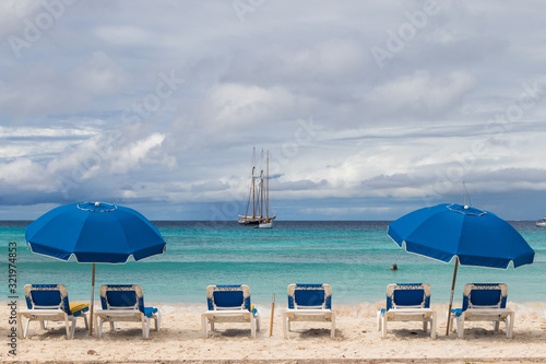 Blue beach chairs and umbrellas, ocean view, boats © Brigitte