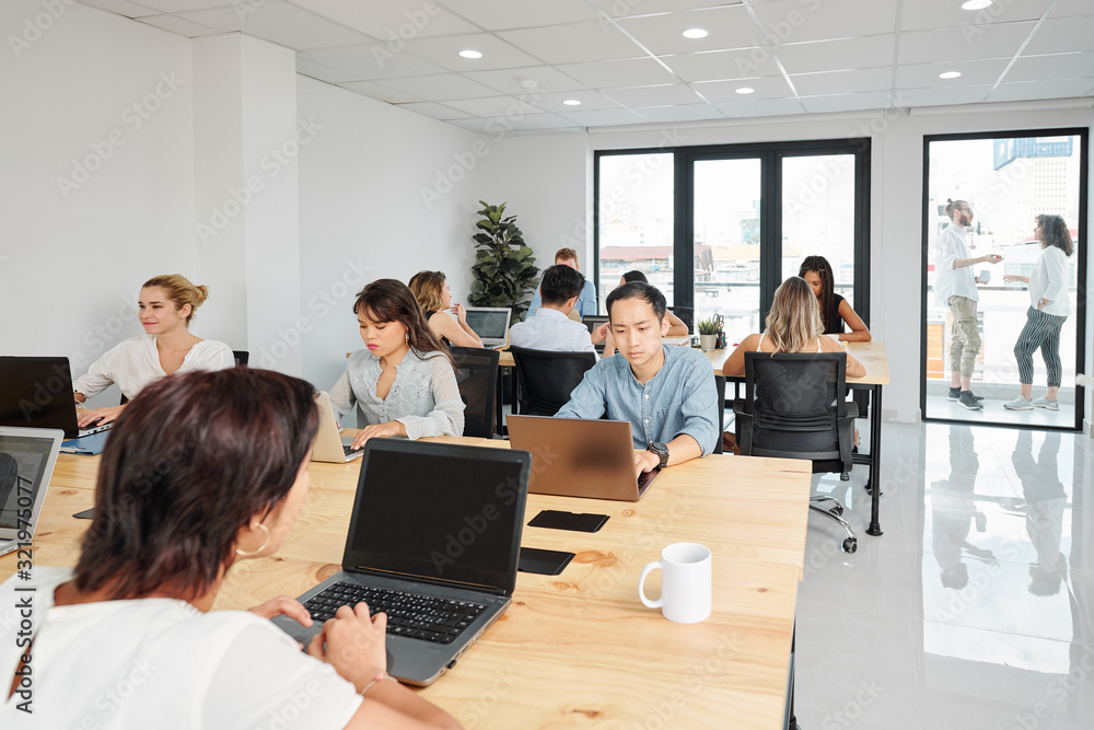 Open space office of IT company with many software developers working on one big project Open space office of IT company with many software developers working on one big project