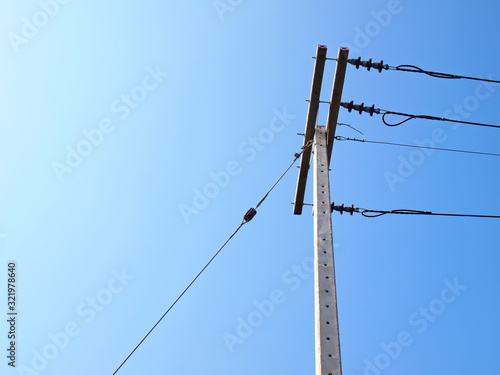 Guy Wire and high voltage cable on the pole It is a cable for fixing the tension of the post and the electrical cable to adjust the balance in the last column. On the blue sky background