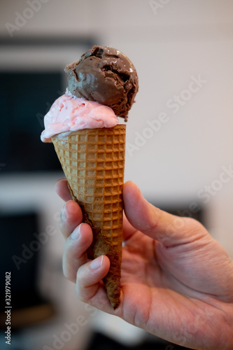 Wafer cone with two scoops of ice cream strawberry and chocolate