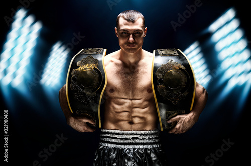 Kickboxing world middleweight champion stands with two belts. The concept of a healthy lifestyle, victory, success. Motivation. photo