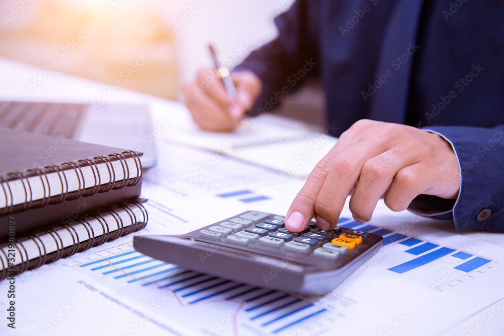 Businessman hands using calculator and Financial data analyzing at the office. Businessman hands using calculator and Financial data analyzing at the office.