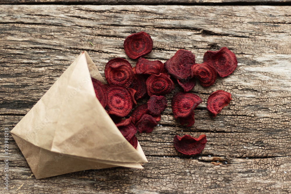 Homemade beetroot chips. Snacks are wrapped in a paper bag. Handmade healthy vegetable chips. Natural healthy snack Homemade beetroot chips. Snacks are wrapped in a paper bag. Handmade healthy vegetable chips. Natural healthy snack