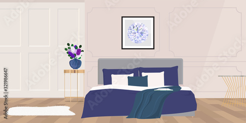 Flowers in vase on bedside table next to king size bed with navy blue bedding