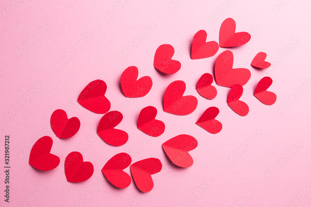A lot of small hearts of red color against on a pink background. Happy Valentine's Day.