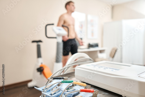 Clothespins of the ECG machine in the foreground. Athlete does a cardiac stress test and VO2 in a medical study, monitored by the doctor. photo