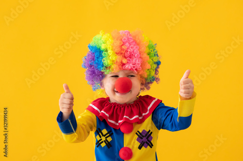 Fototapeta Funny kid clown playing against yellow background