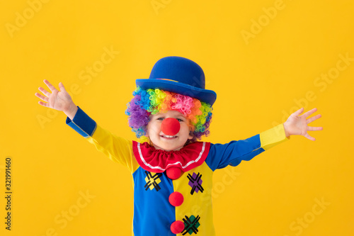 Obraz na plátne Funny kid clown playing against yellow background