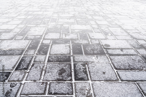 Grey granite stone walkway covered with snow. Pavement texture.