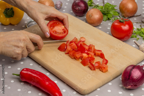 Hands chop tomatoes on cutting board