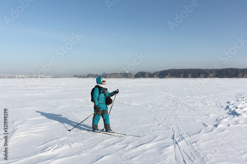 Happy woman with a photo bag, backpack and video camera, skiing on the snow surface on a frozen river, Ob reservoir, Novosibirsk, Russia