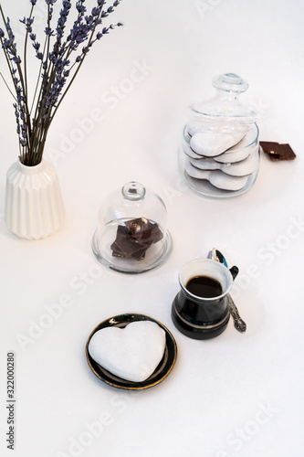 Valentine's Day still life with cup of coffee, chokolate and plate with heart shaped ginger cookie on white background. Valentines Day celebration concept