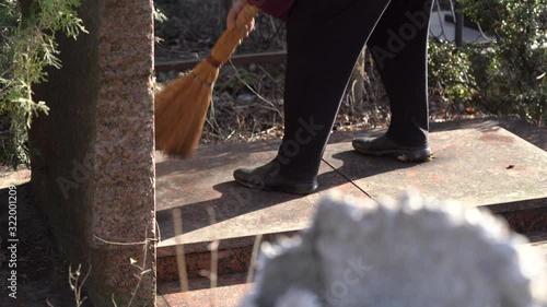 Elderly woman visiting cemetery. Woman cleans debris from granite tombstone. Abdal Cemetery in Simferopol. photo