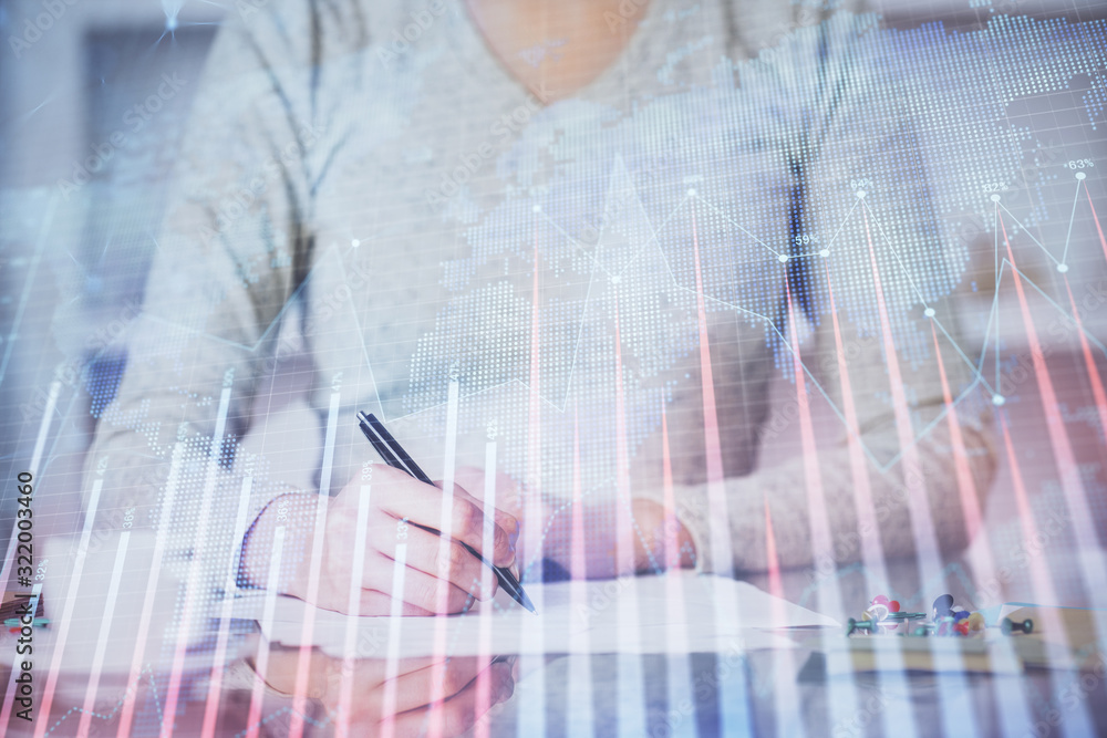 Hand taking notes in notepad. Forex chart holograms in front. Concept of research. Double exposure Hand taking notes in notepad. Forex chart holograms in front. Concept of research. Double exposure
