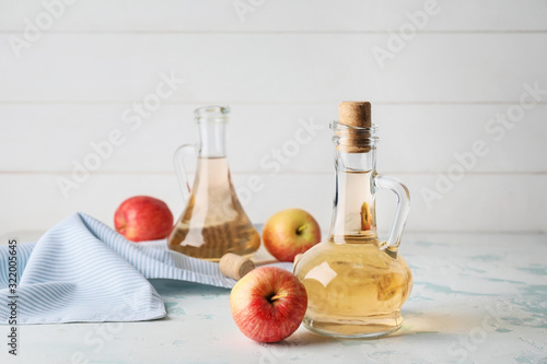 Foto Bottles of apple cider vinegar on white table