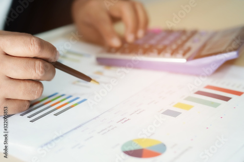 Asian accountant working and analyzing financial reports project accounting with chart graph and calculator in modern office : finance and business concept.