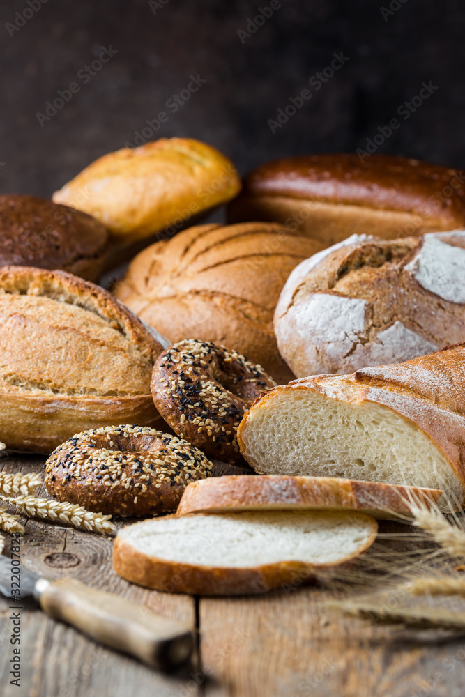 Assortment of fresh baked bread and buns on wooden table background Assortment of fresh baked bread and buns on wooden table background