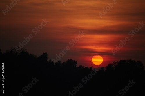 Beautiful picture of tree silhouettes with the sun behind the clouds during the golden sunset photo