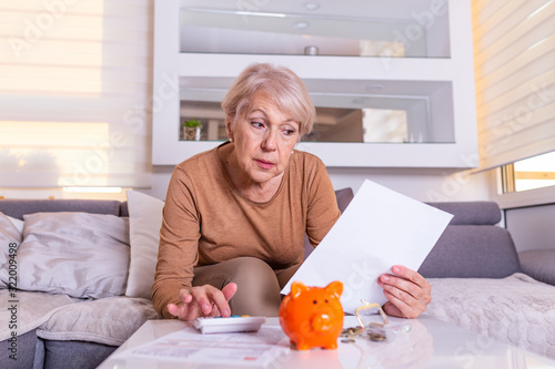 Foto Senior old woman shocked with the bills she receives, appalled and gasping