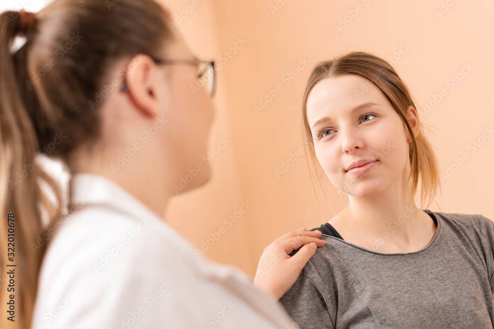 Caring physiotherapist or a doctor consulting with her young female patient at her office. Caring physiotherapist or a doctor consulting with her young female patient at her office.