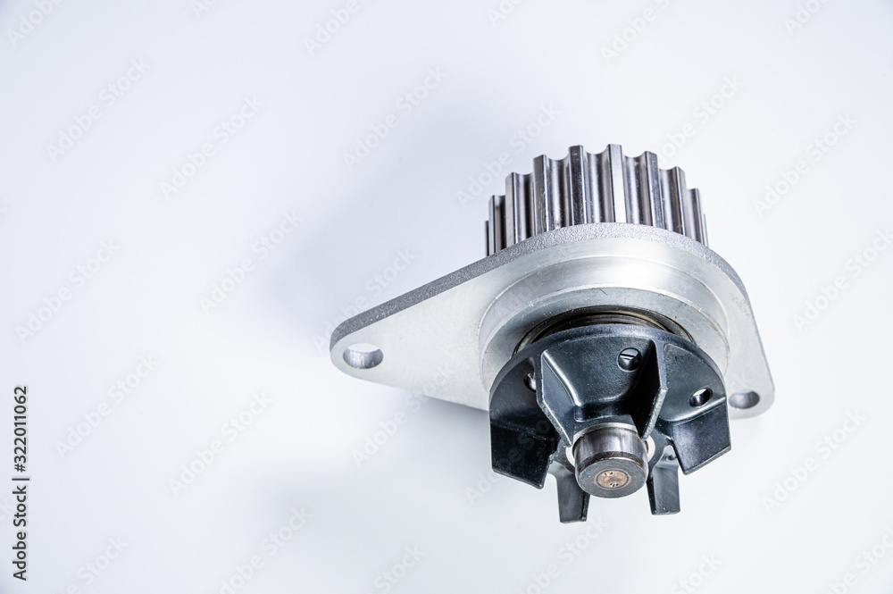 New metal automobile pump for cooling the engine of a water pump on a gray background. The concept of new spare parts for the car engine New metal automobile pump for cooling the engine of a water pump on a gray background. The concept of new spare parts for the car engine