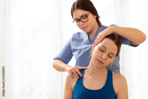 Tableau sur toile Female physiotherapist or a chiropractor adjusting patients neck