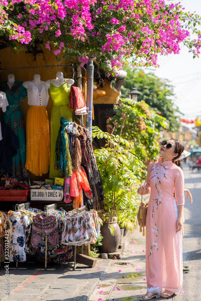 Obraz premium Beautiful women in Vietnamese dressed standing at street in Hoi An
