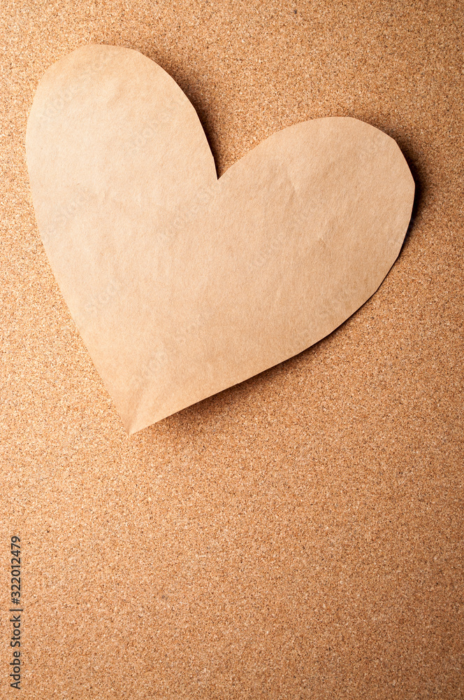 Plain brown paper heart cutout stuck to cork bulletin board for romantic Valentine's Day messages Plain brown paper heart cutout stuck to cork bulletin board for romantic Valentine's Day messages